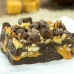 Caramel Filled Brownies on parchment paper with caramel squares in the background