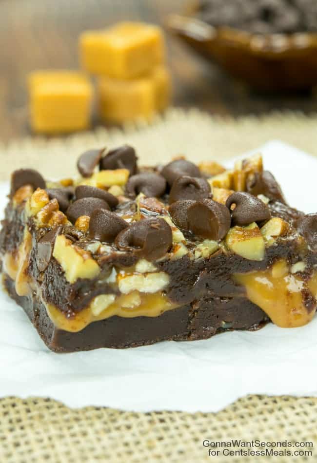 Caramel Filled Brownies on parchment paper with caramel squares in the background