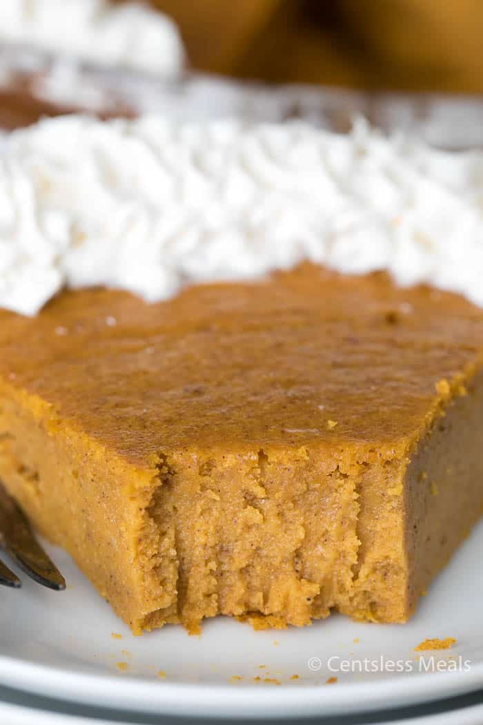 Crustless pumpkin pie on a white plate with a bite taken out