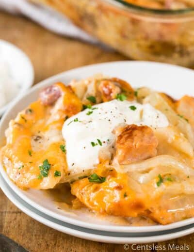Pierogi casserole on a white plate with sour cream and parsley