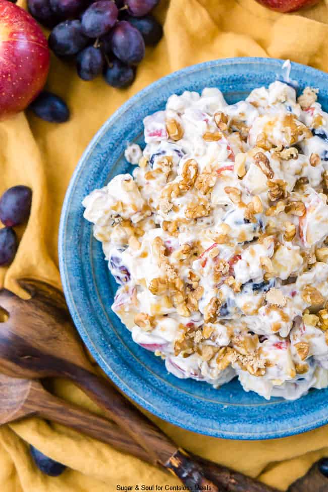 Apple walnut salad in a blue bowl with utensils on the side