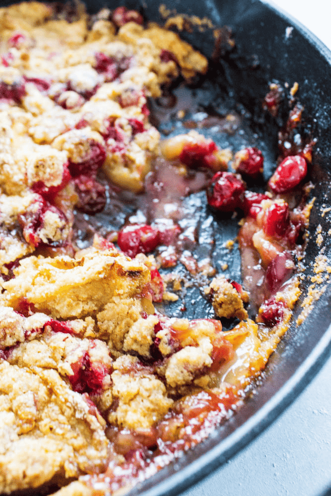 Apple cranberry crisp in a pan with a scoop taken out