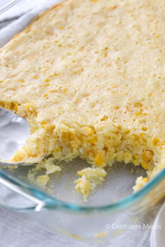 Cream corn casserole in a casserole dish with some being scooped out