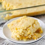 Creamed corn casserole on a white plate with the casserole dish on the side