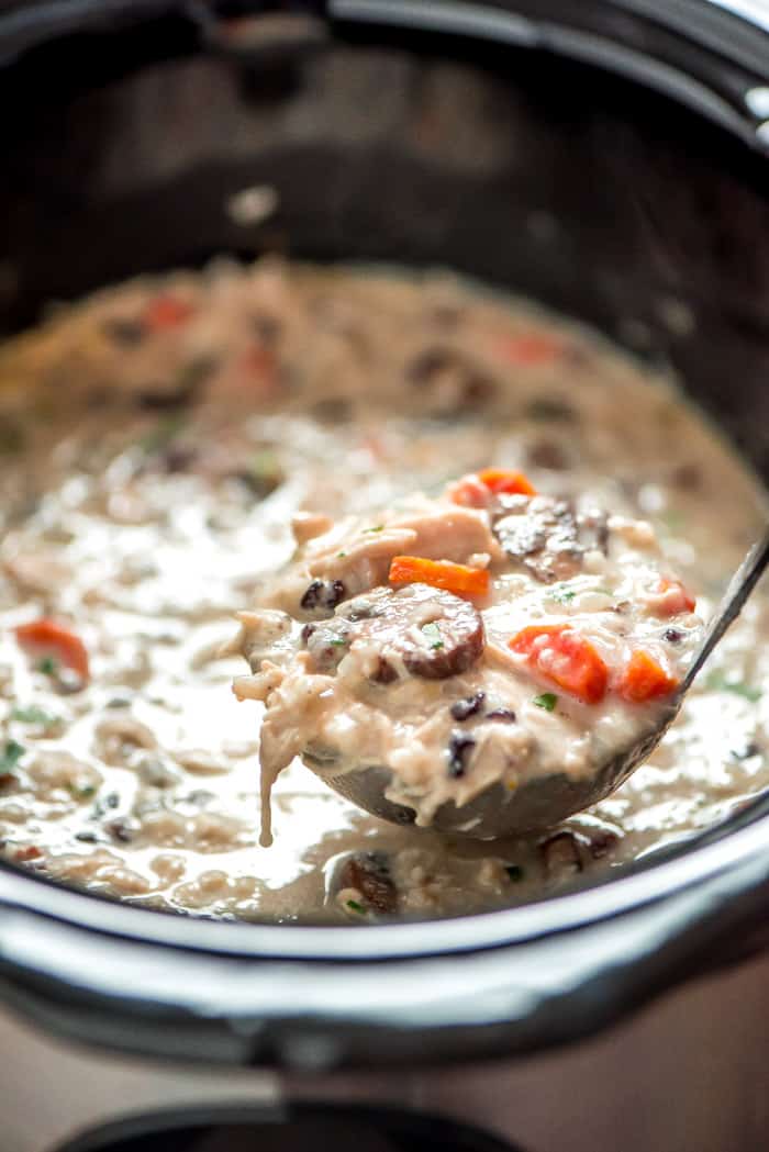 Slow cooker chicken wild rice soup in a slow cooker being scooped with a ladle