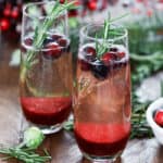 Cranberry mimosas in glasses with cranberries and rosemary as garnish