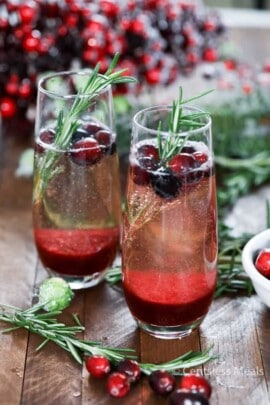 Cranberry mimosas in glasses with cranberries and rosemary as garnish