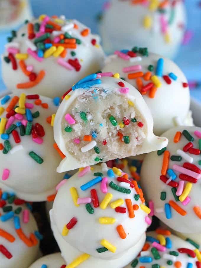 No bake cake batter truffles with sprinkles and a bite taken out of 1