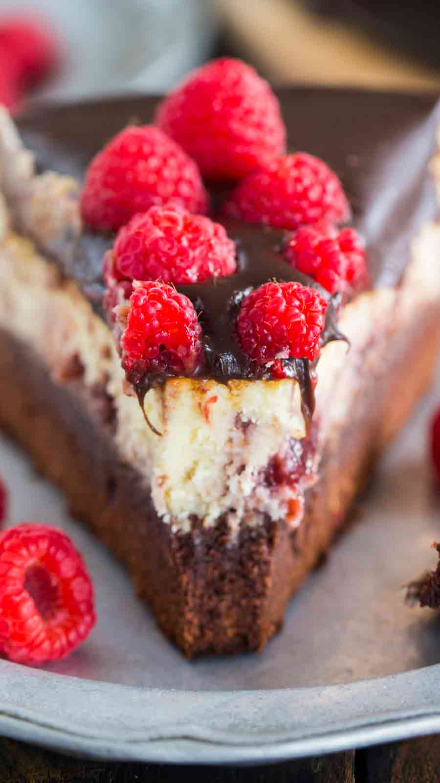 Closeup of Brownie Bottom Raspberry Cheesecake on a plate with a bite taken out of it