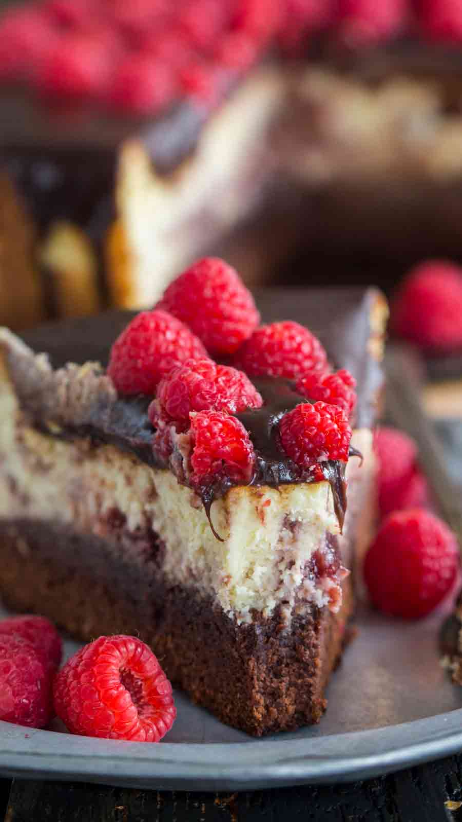 Slice of Brownie Bottom Raspberry Cheesecake on a plate with a bite taken out of it