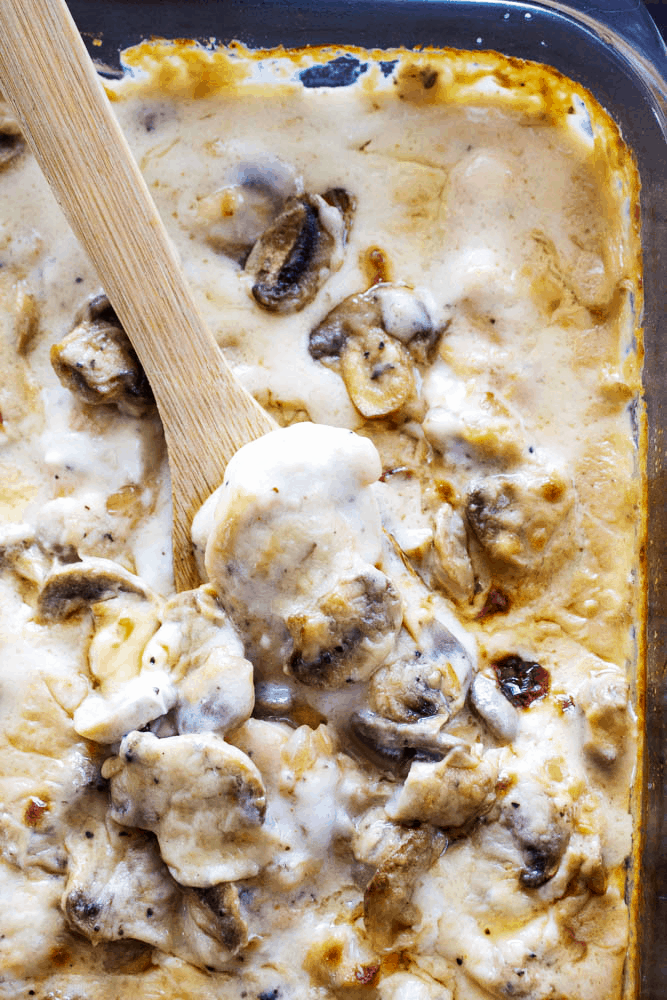 Overhead shot of Chicken and Mushroom Casserole in baking dish with a wooden spoon