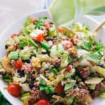 Pouring avocado dressing over a taco salad bowl