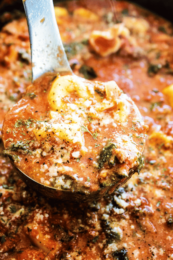 Slow cooker Tuscan tortellini soup in a slow cooker with a ladle