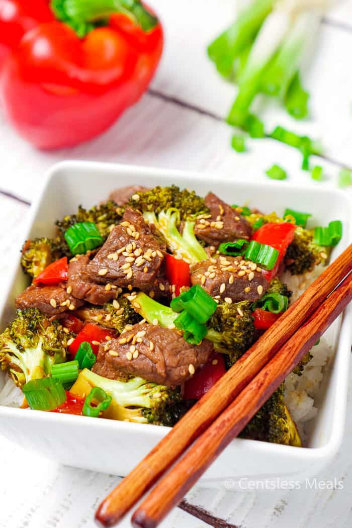 Slow cooker beef and broccoli in a white bowl with chopsticks