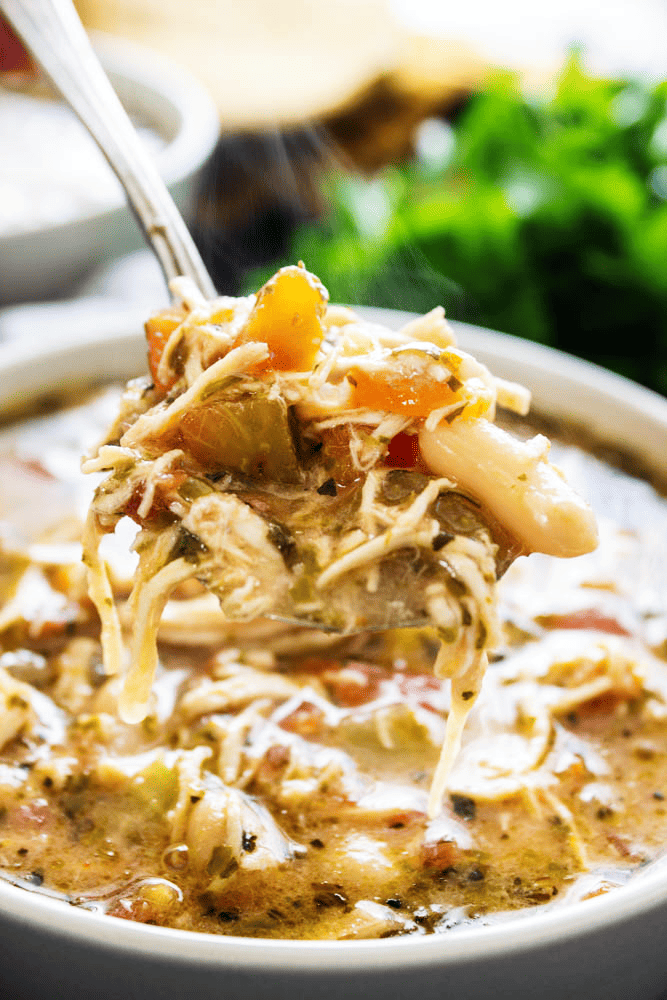 Slow cooker chicken soup in a bowl with a spoonful being taken out