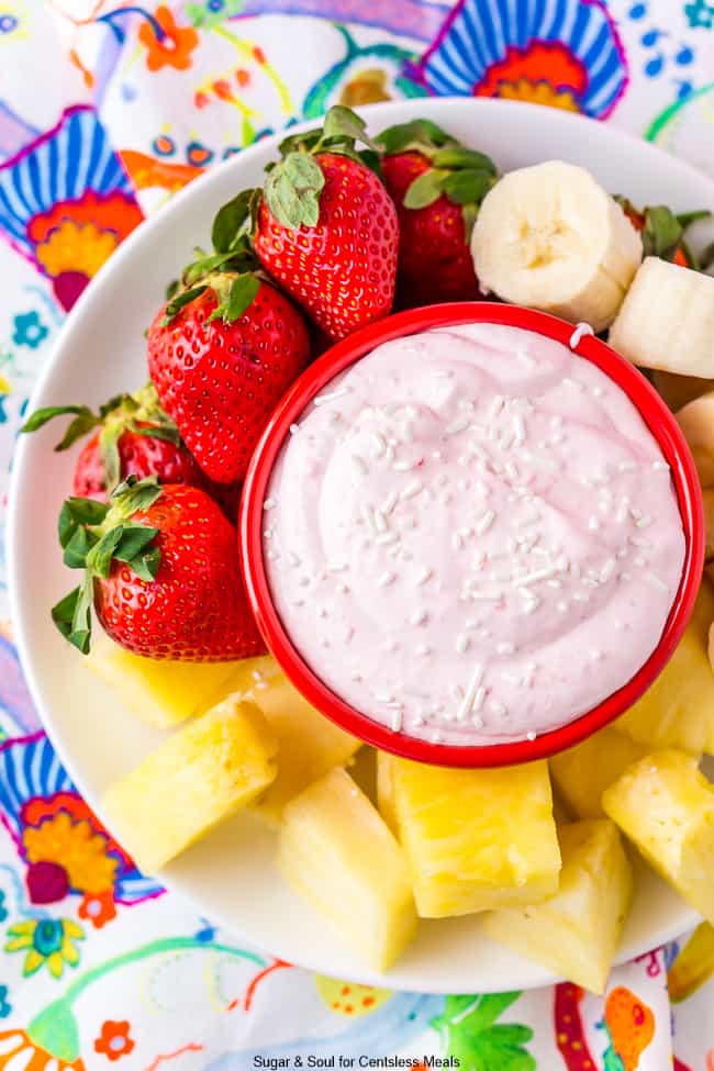 Strawberry fruit dip in a bowl with fruit on the side of a white plate