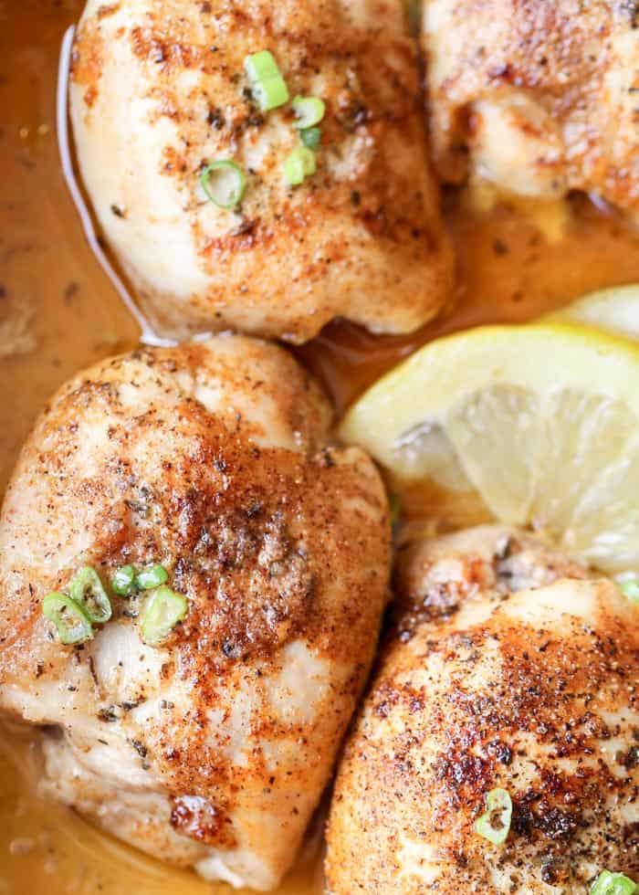 Baked lemon butter chicken thighs in a dish with lemon slices