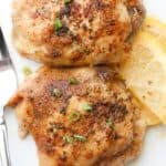Baked lemon butter chicken thighs on a plate with green onions