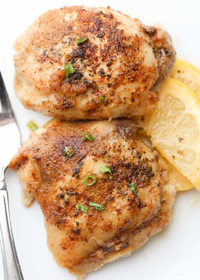 Baked lemon butter chicken thighs on a plate with green onions