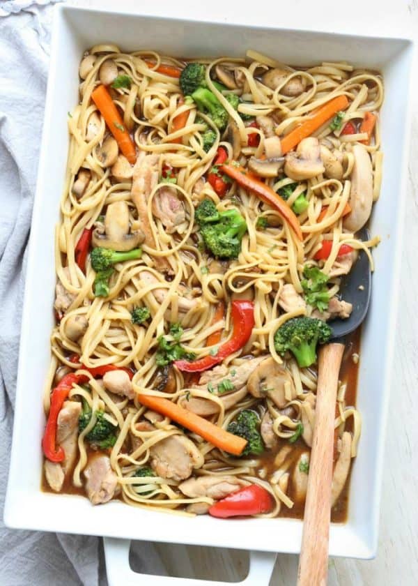 Chicken vegetable and pasta stir fry in a casserole dish with a spoon