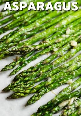 Oven Roasted Asparagus lined up on parchment paper with writing.