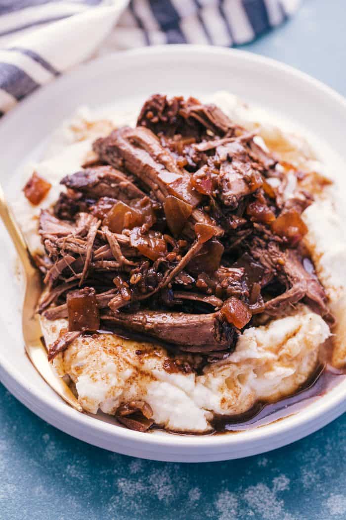 Slow cooker balsamic glazed roast beef on a plate with mashed potatoes and a fork