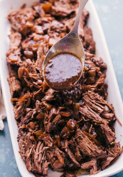 slow cooker roast beef in a dish with sauce on a spoon
