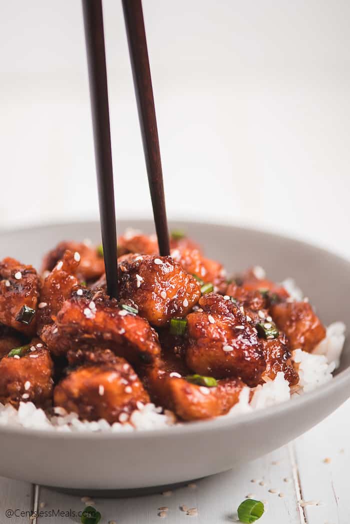 Instant pot honey garlic chicken in a bowl with rice green onions and chopsticks