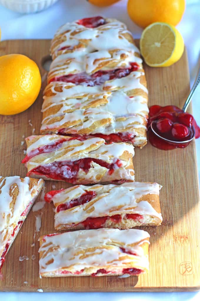 Lemon cherry cheese danish on a wooden board with lemon and cherries