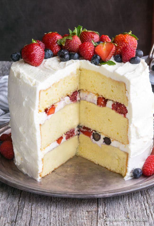 Berry Chantilly cake with berries on top and a piece taken out