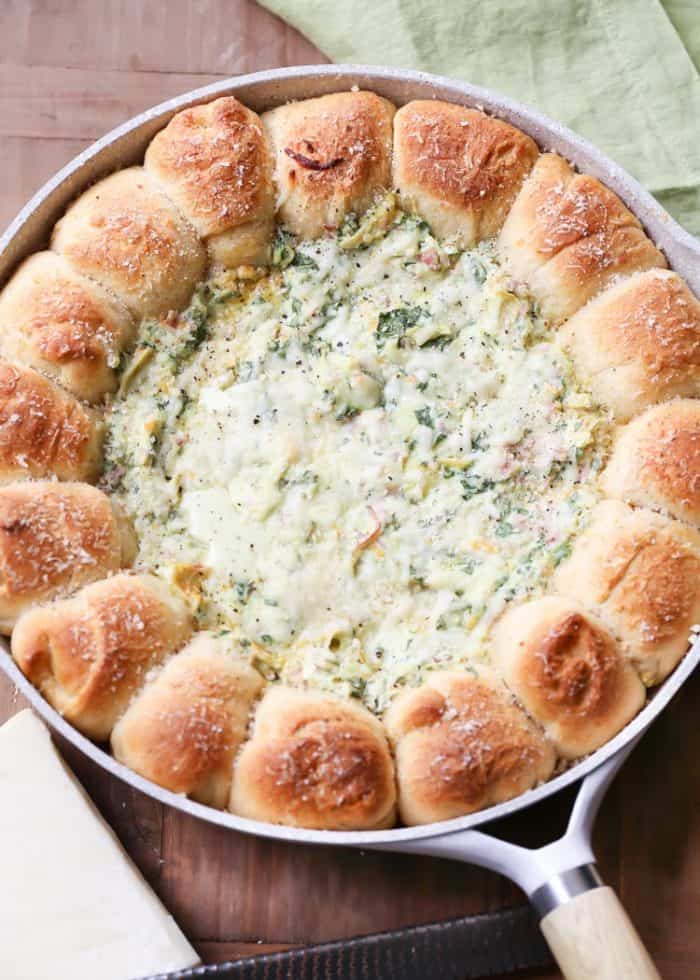 Pull-A-Part crescents with spinach artichoke dip in a skillet on a wooden board