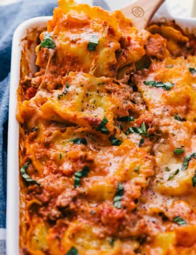 cheese ravioli in a casserole dish with a wooden spoon