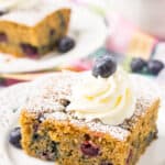 Overnight blueberry coffee cake on a plate with icing and a blueberry on top