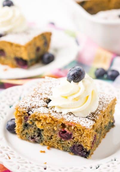 Overnight blueberry coffee cake on a plate with icing and a blueberry on top