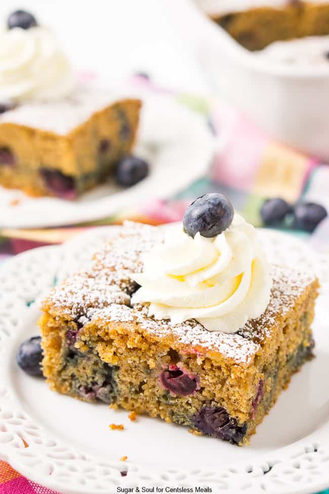 Overnight blueberry coffee cake on a plate with icing and a blueberry on top