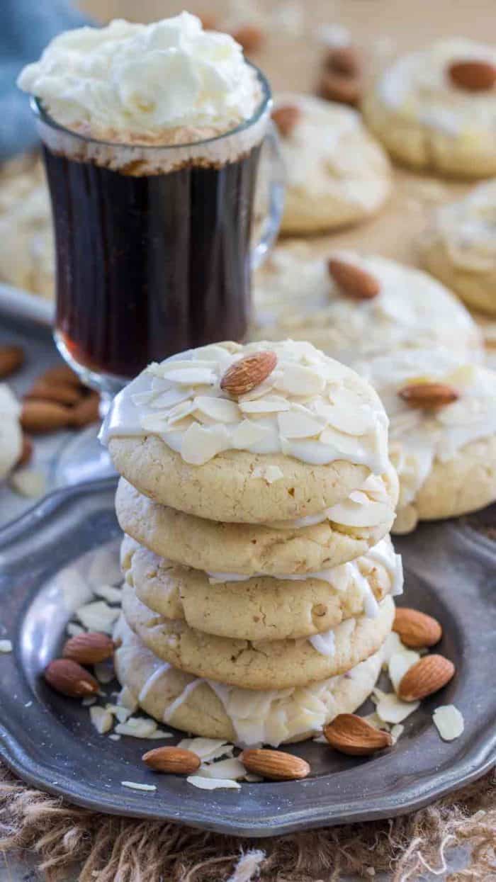Buttery almond cookies on a plate with a cup of coffee in the background