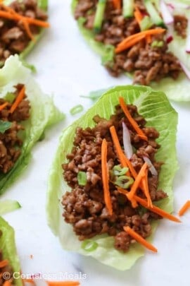 Chicken lettuce wraps with carrots green onions and radishes on top