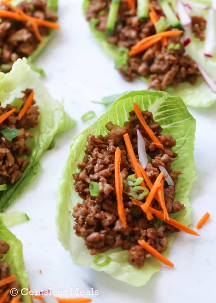 Chicken lettuce wraps with carrots green onions and radishes on top