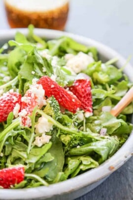 Spinach strawberry salad in a bowl topped with cheese