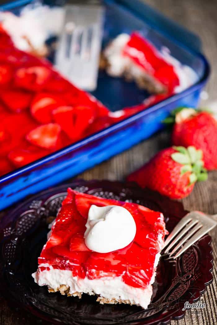 Strawbery Pretzel Salad in a dish and on a plate with whipped cream on top