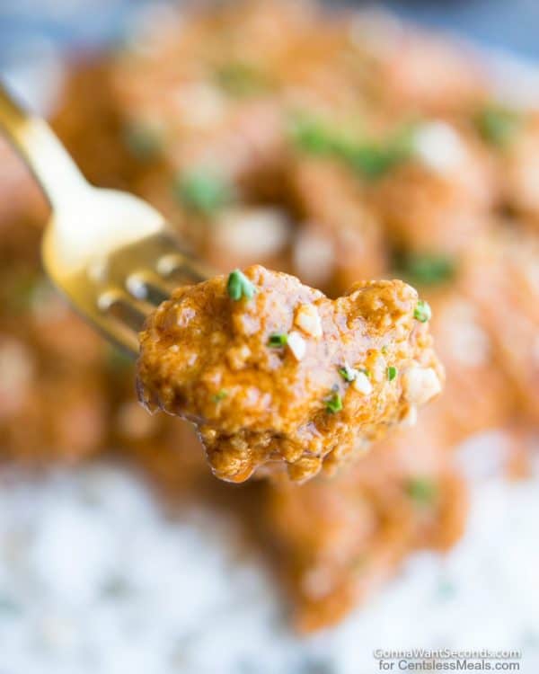 Butter chicken on fork garnished with cilantro and cashews