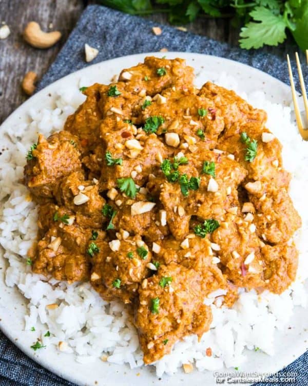 Butter chicken on a bed of white rice, garnished with cilantro and cashews