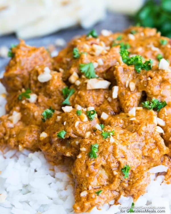 Butter chicken on a bed of white rice, garnished with cilantro and cashews