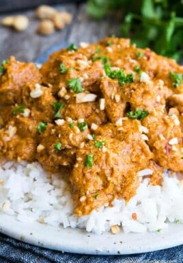 Butter chicken on a bed of white rice, garnished with cilantro and cashews