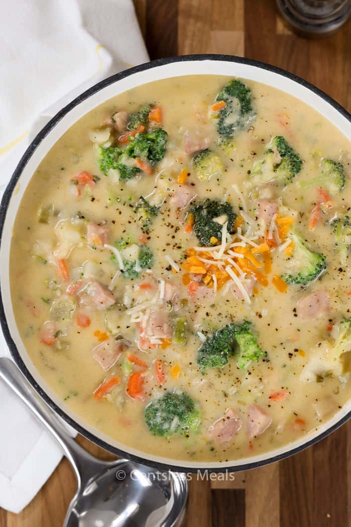 Ham potato soup in a white bowl with a spoon on the side