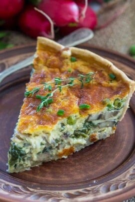 Spinach quiche on a plate garnished with thyme and green onions