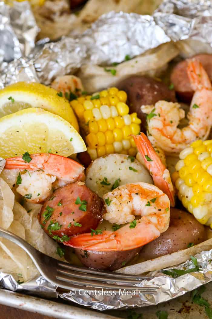 Shrimp boil foil packets with a fork and lemon slices