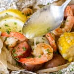 Butter being poured on shrimp boil foil packets