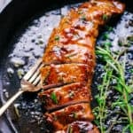 Garlic honey roasted pork loin in a pan with sauce and a fork