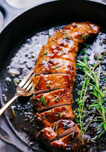 Garlic honey roasted pork loin in a pan with sauce and a fork